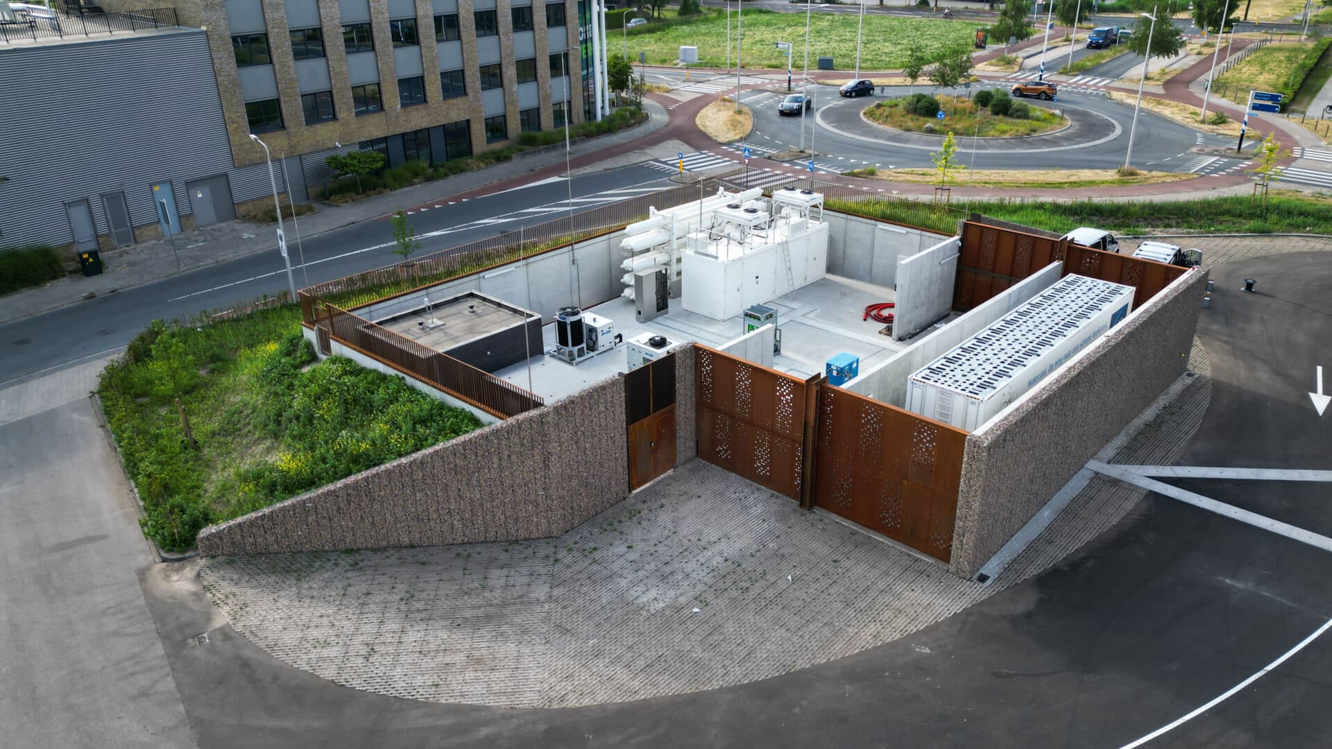 Betonstützwände rund um eine technische Versorgungsanlage in einem urbanen Umfeld mit Straßenkreuzung und Bebauung