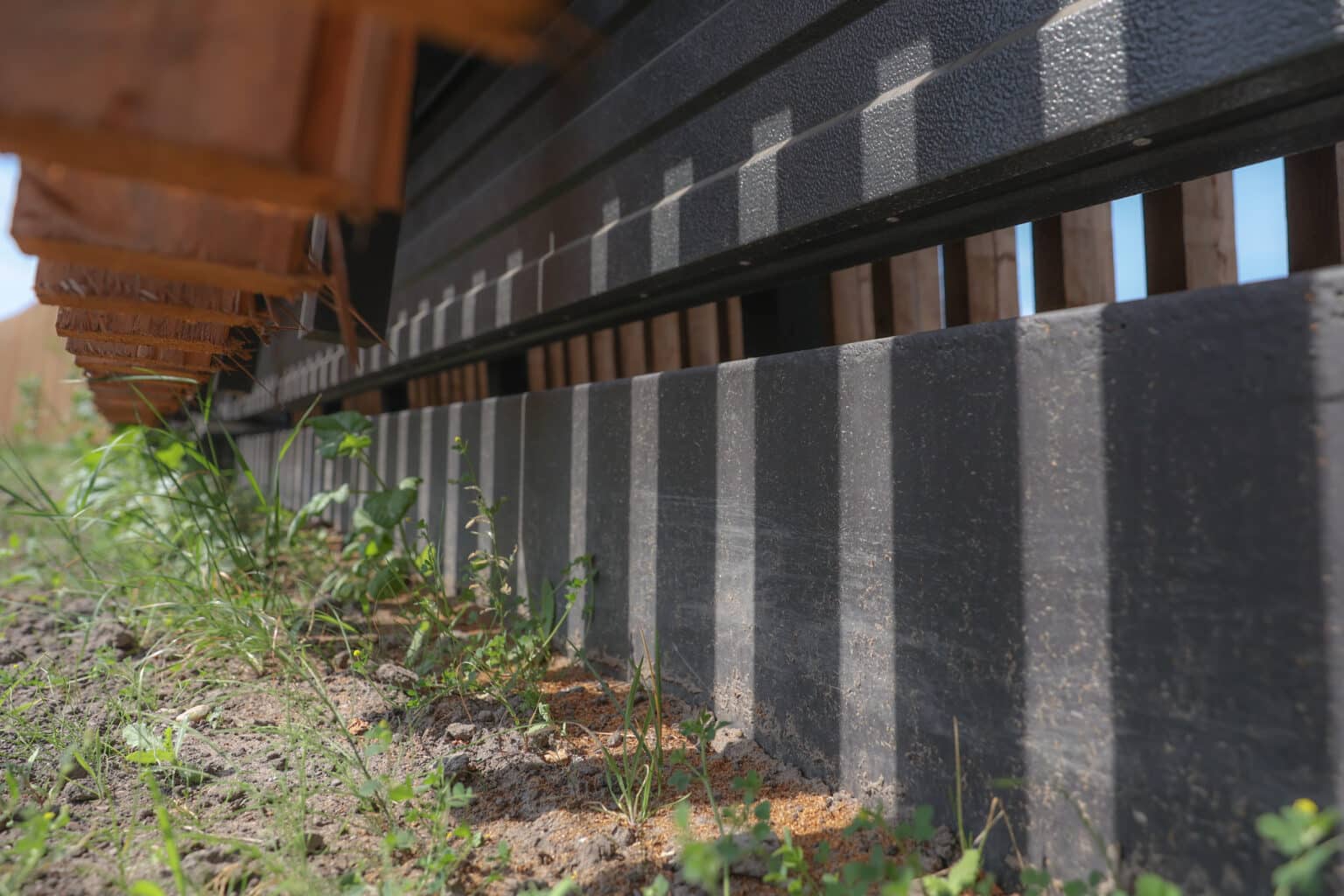 Unterkonstruktion einer Lärmschutzwand mit Betonstützen und Holzverkleidung.