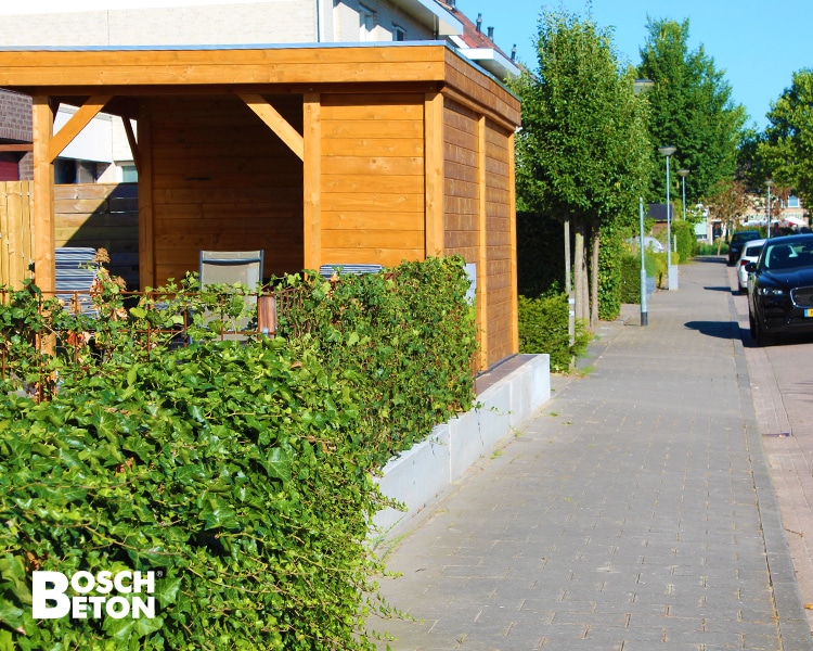 Betonstützwände entlang eines Gehwegs mit Hecke und Holzkonstruktion im Wohnumfeld