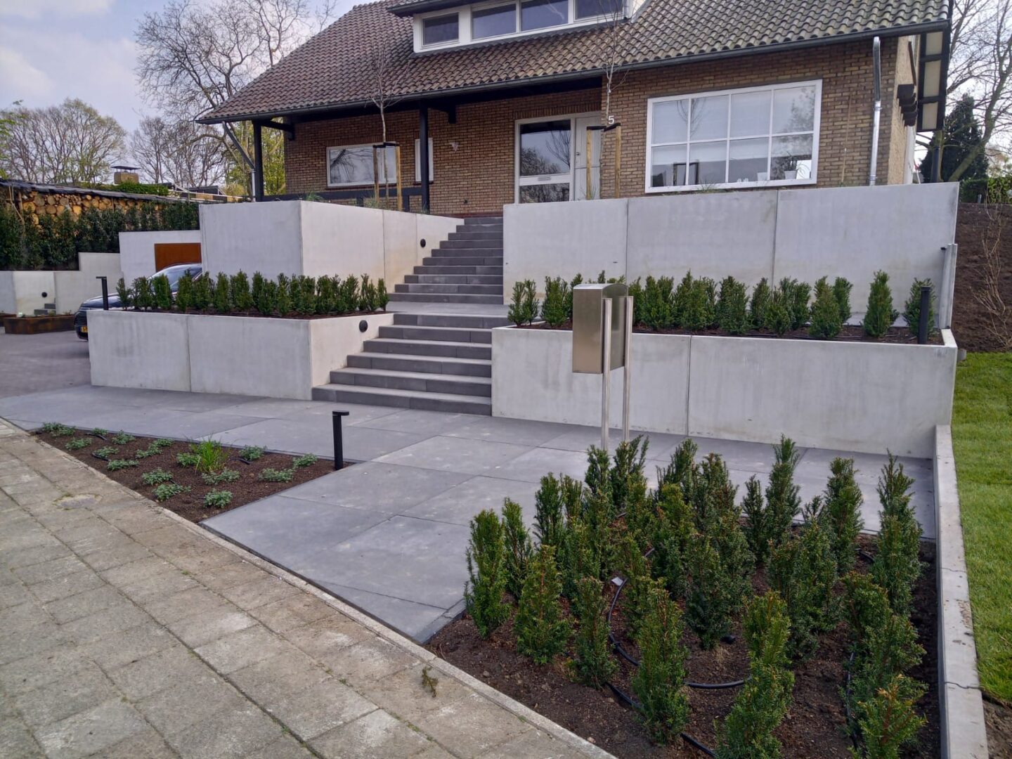 Beton-Stützwinkel zur Terrassierung eines Gartens mit Treppenanlage vor einem Wohnhaus