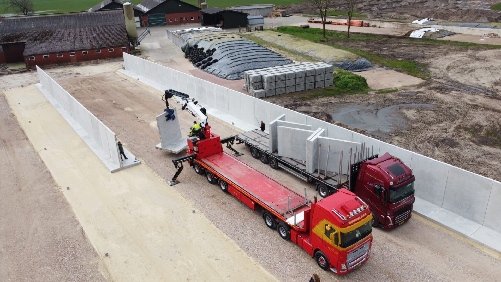 Stützwände werden auf der Baustelle eines Fahrsilos mit einem Kran direkt vom Lkw versetzt.
