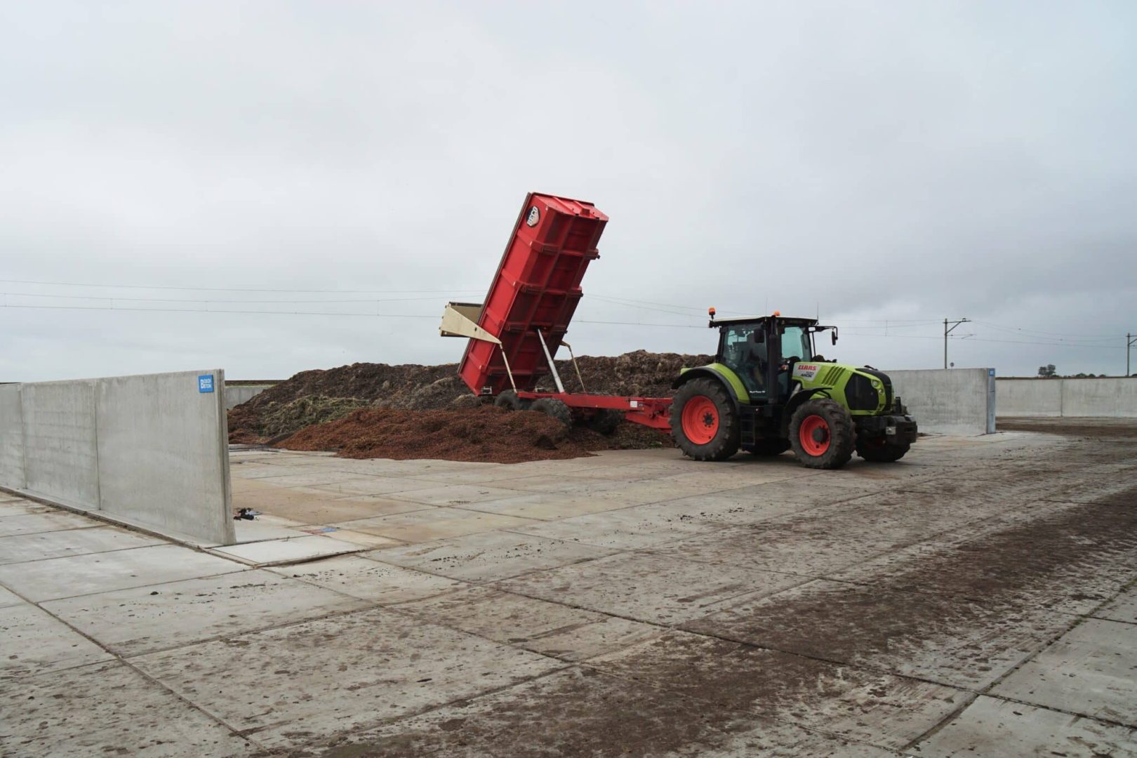 Einlagerung von Silage in einem Fahrsilo mit Stützwänden.