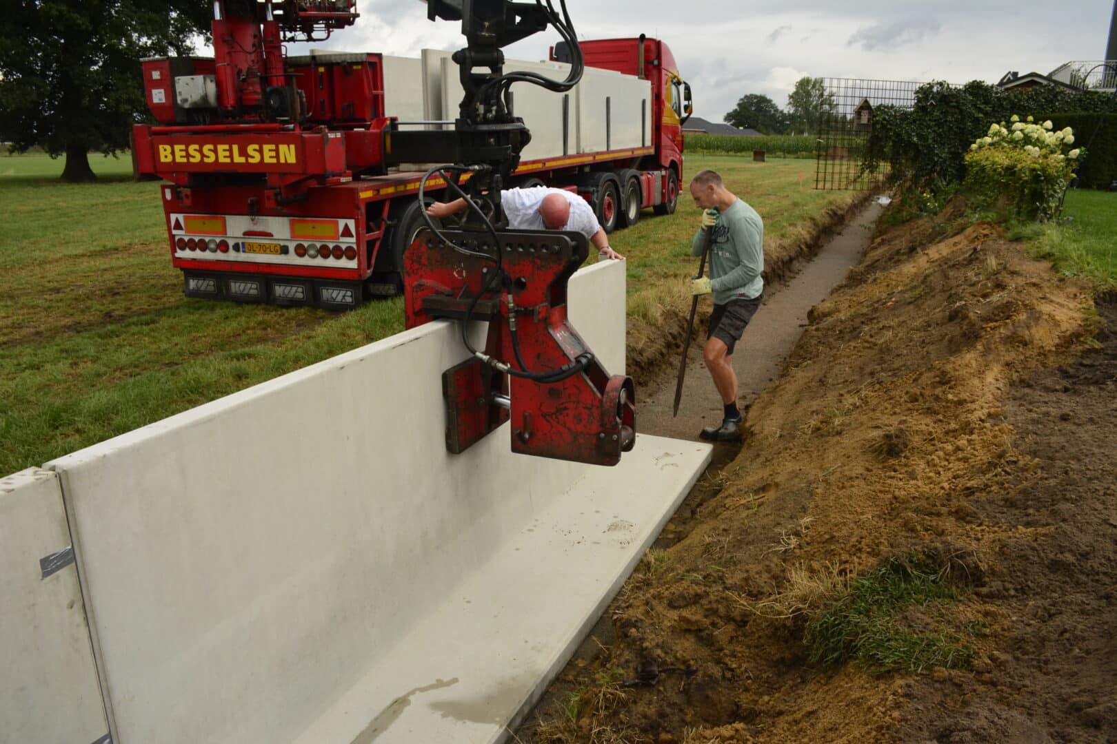 Lkw setzt Stützwände entlang eines Geländesprungs auf einer Baustelle