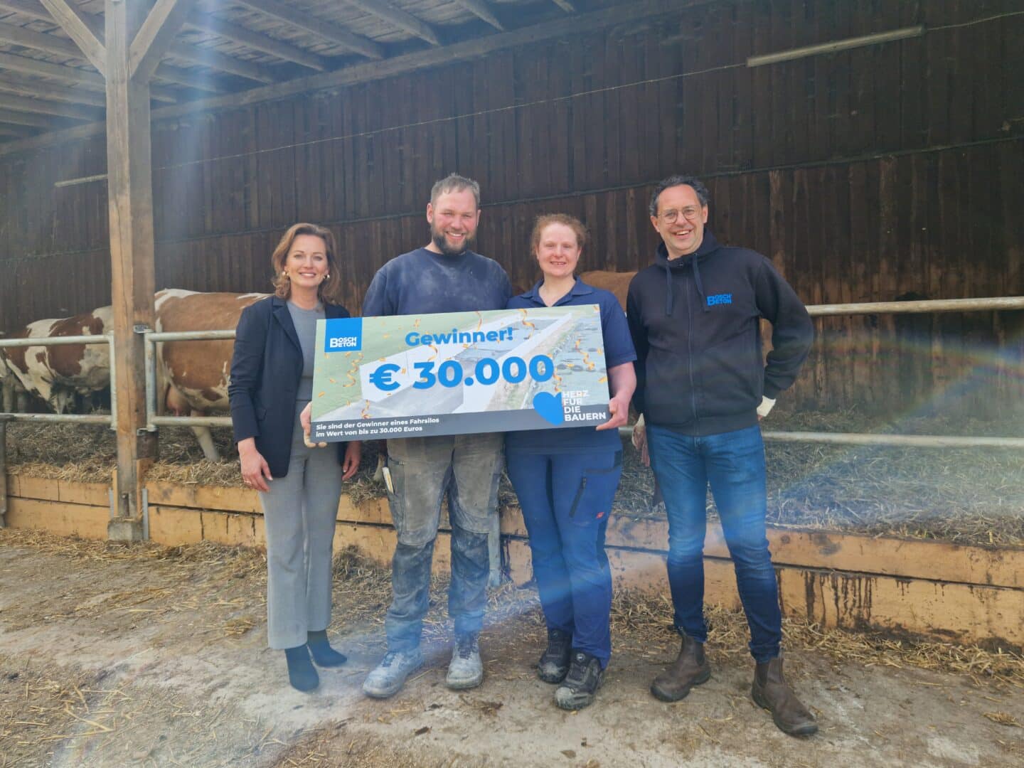 Gewinner der Bosch Beton Fahrsilo-Aktion mit symbolischem Gewinnscheck vor einem Stallgebäude