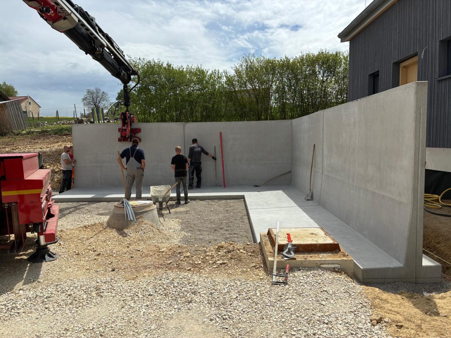 Montage von Stützwänden mit Lkw und Hebegreifer auf einer Baustelle