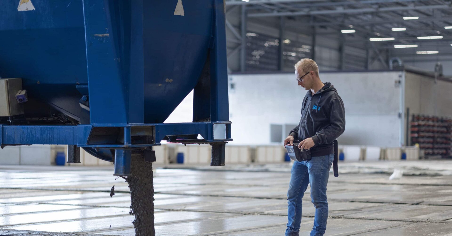 Mitarbeiter überwacht den Zuschnitt eines Betonfertigteils in der Produktionshalle